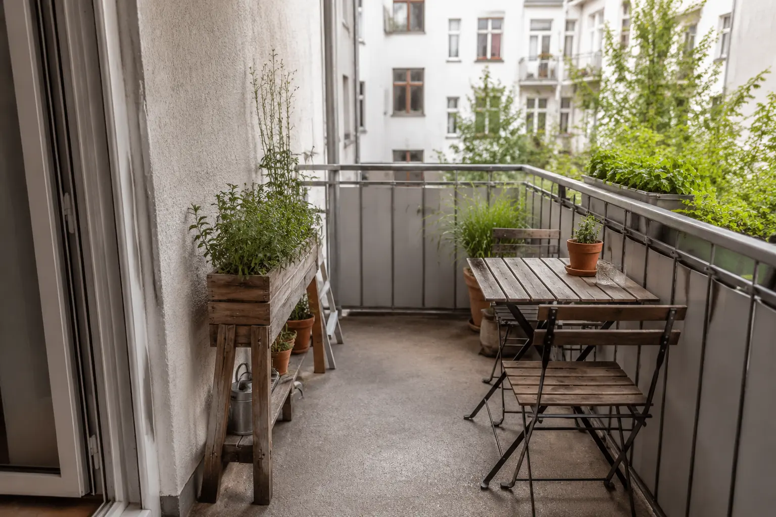 Kleiner Balkon mit Möbeln am Rand und einer klar freien Fläche in der Mitte