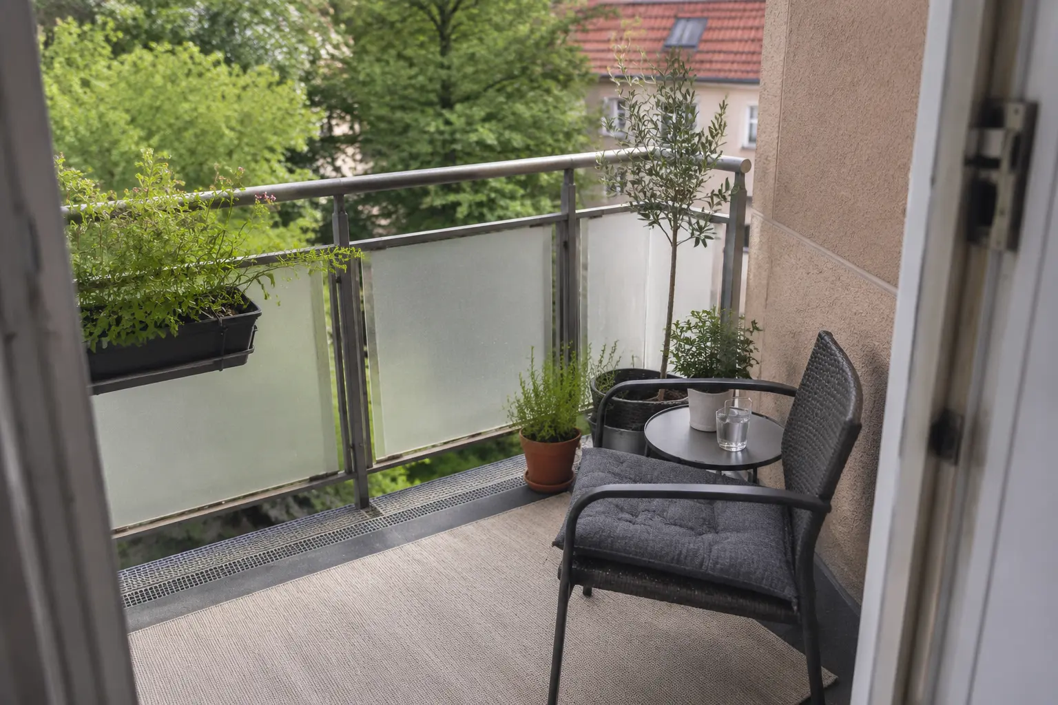 Kleiner Balkon mit flach liegendem Outdoor-Teppich unter einer kompakten Sitzecke